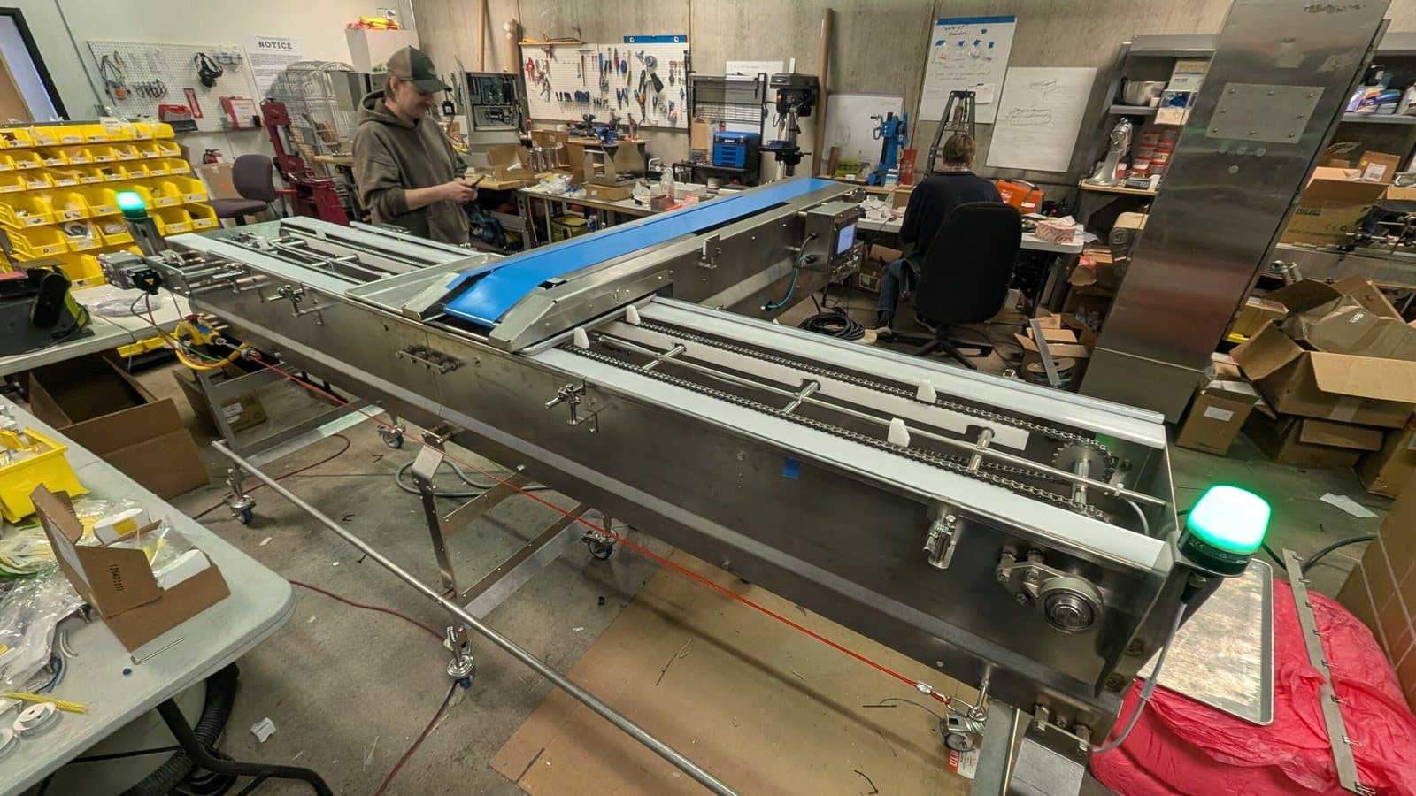 A stainless production machine under assembly in the Launch Partners shop in Arvada, with engineers working at benches behind it