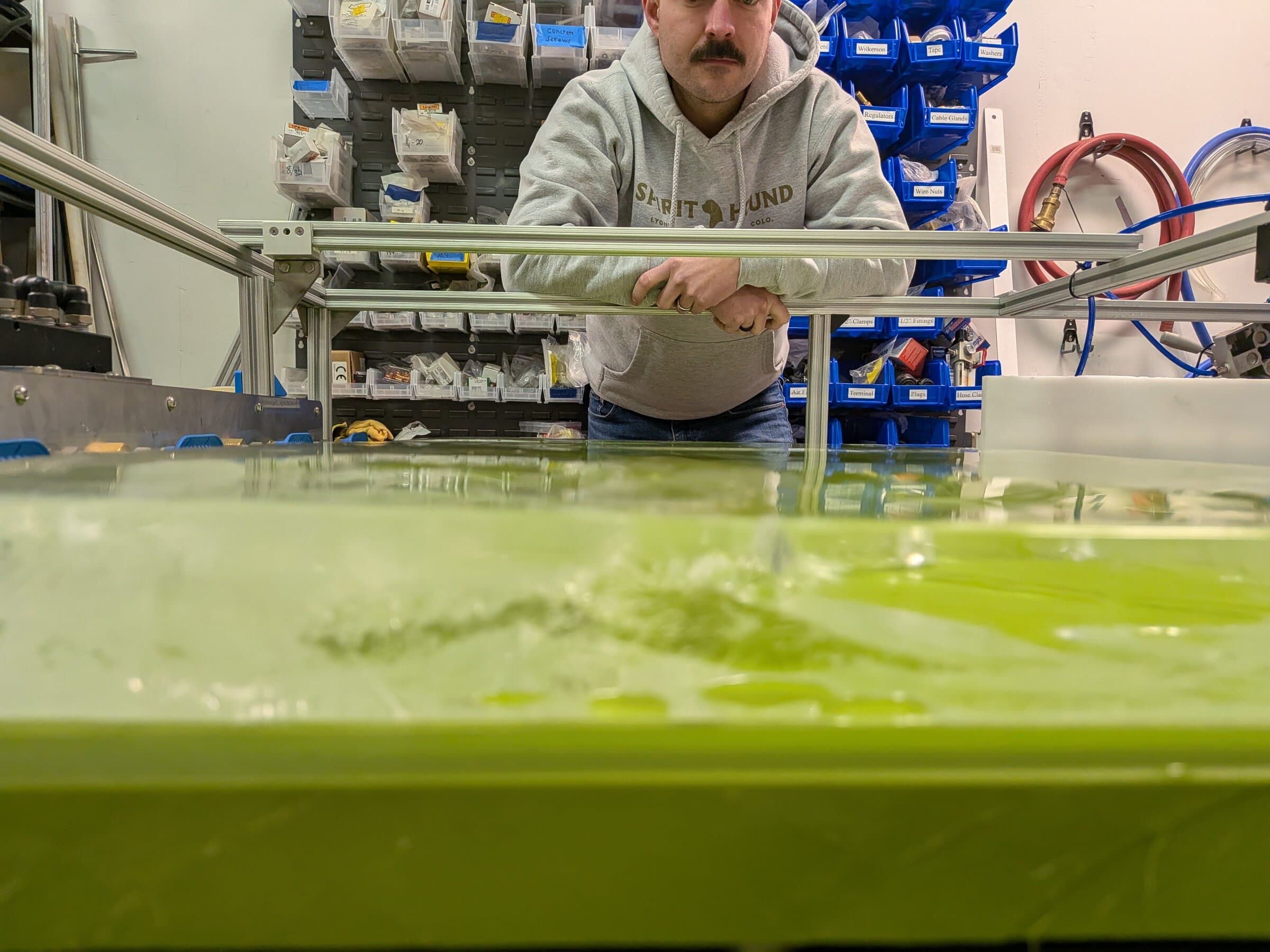 Engineer reaching into a test tank on an R&D rig in the Launch Partners shop